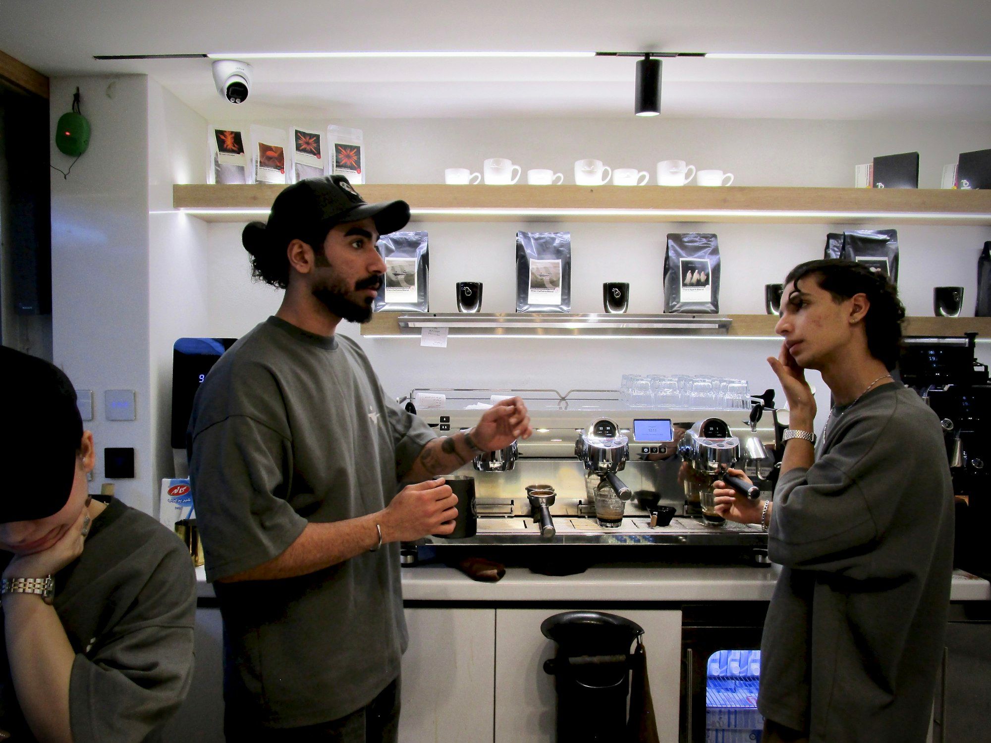 Two cafe owners talking behind the espresso machine counter of their coffee shop