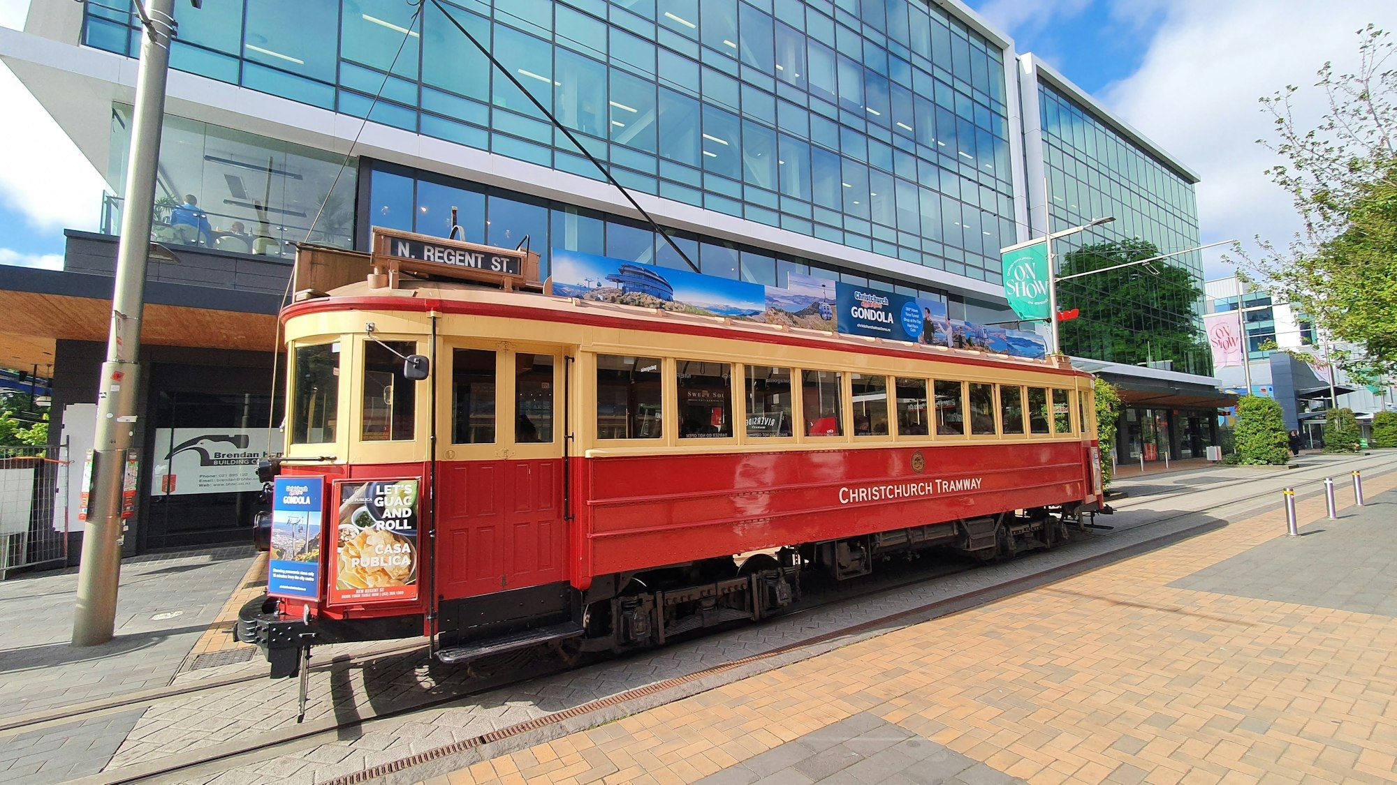 A red and yellow Christchurch heritage tram on a central city street