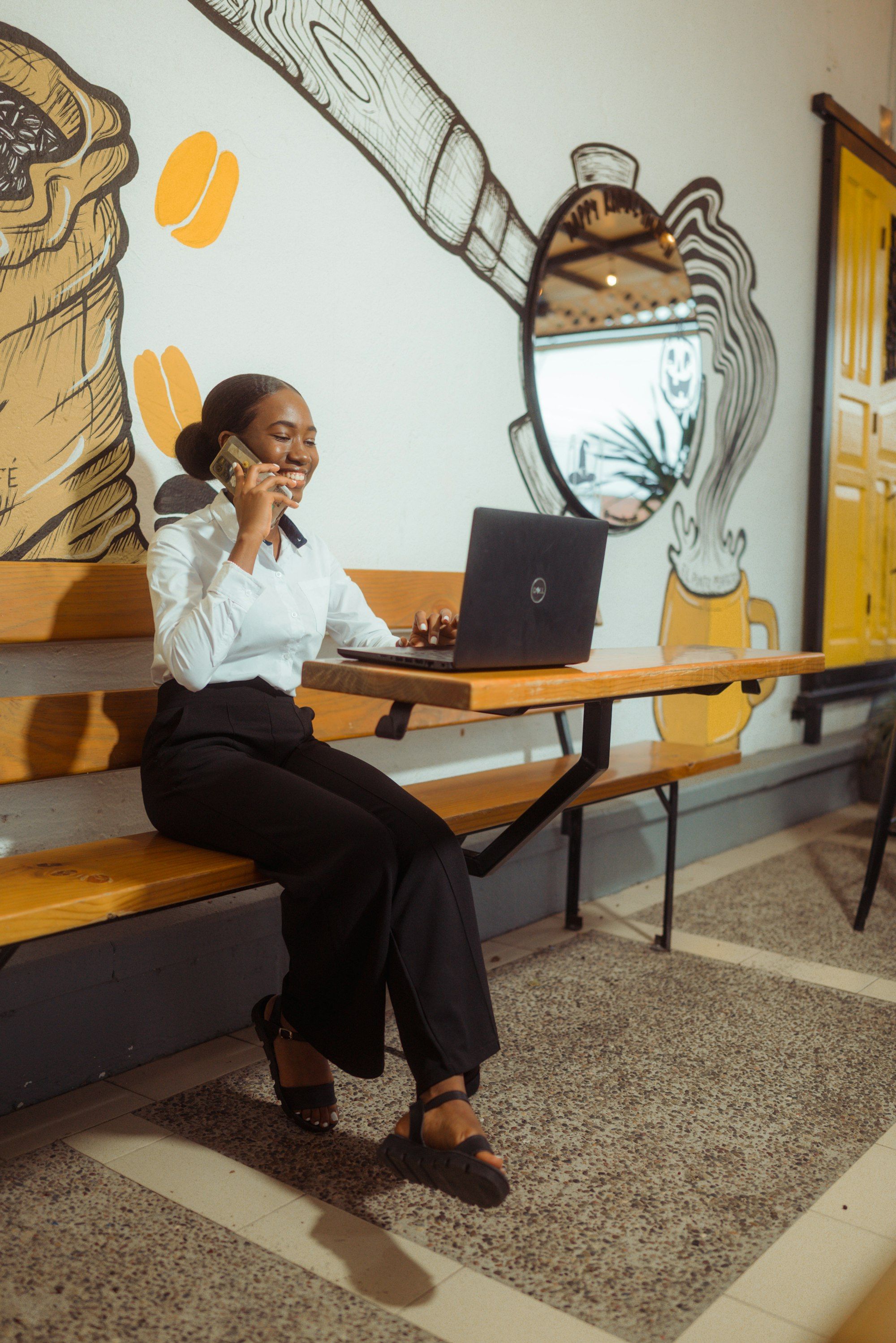 A business owner on the phone while checking figures on her laptop at a cafe table