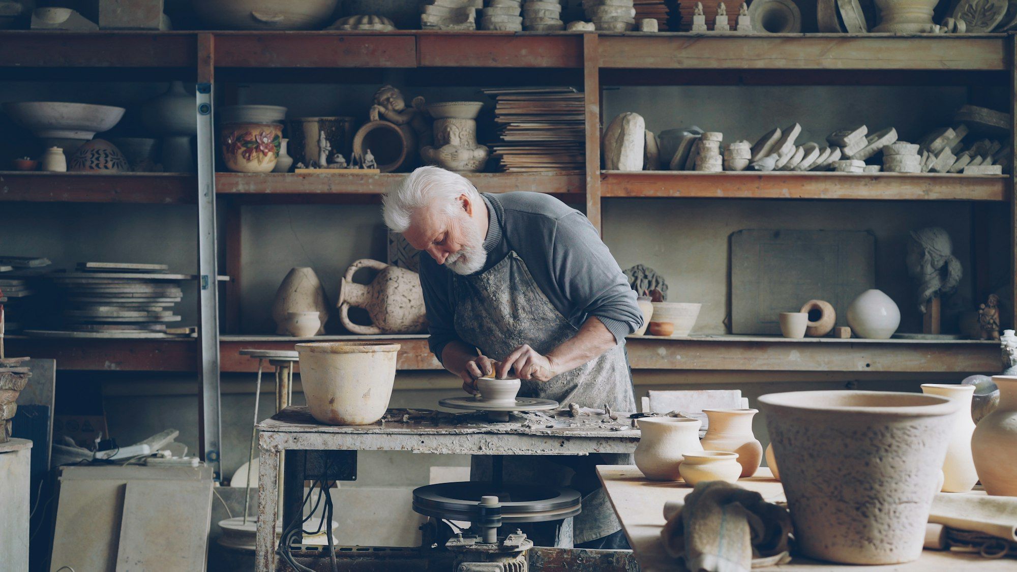 A ceramicist shaping clay on a potter's wheel in his own workshop